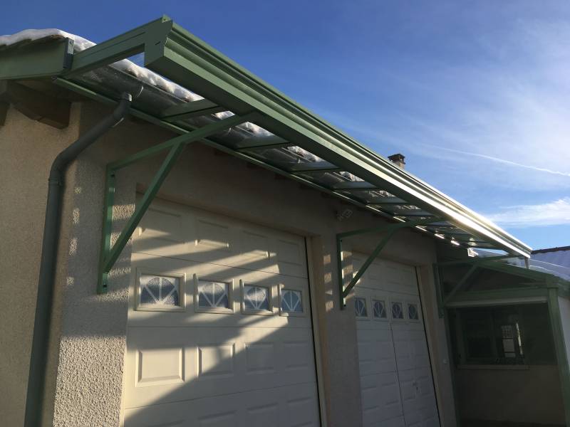 Marquise vitrage alu vert 6021 porte de garage à Saint-Martin-en-Haut : une installation sur mesure signée Boréal Vérandas